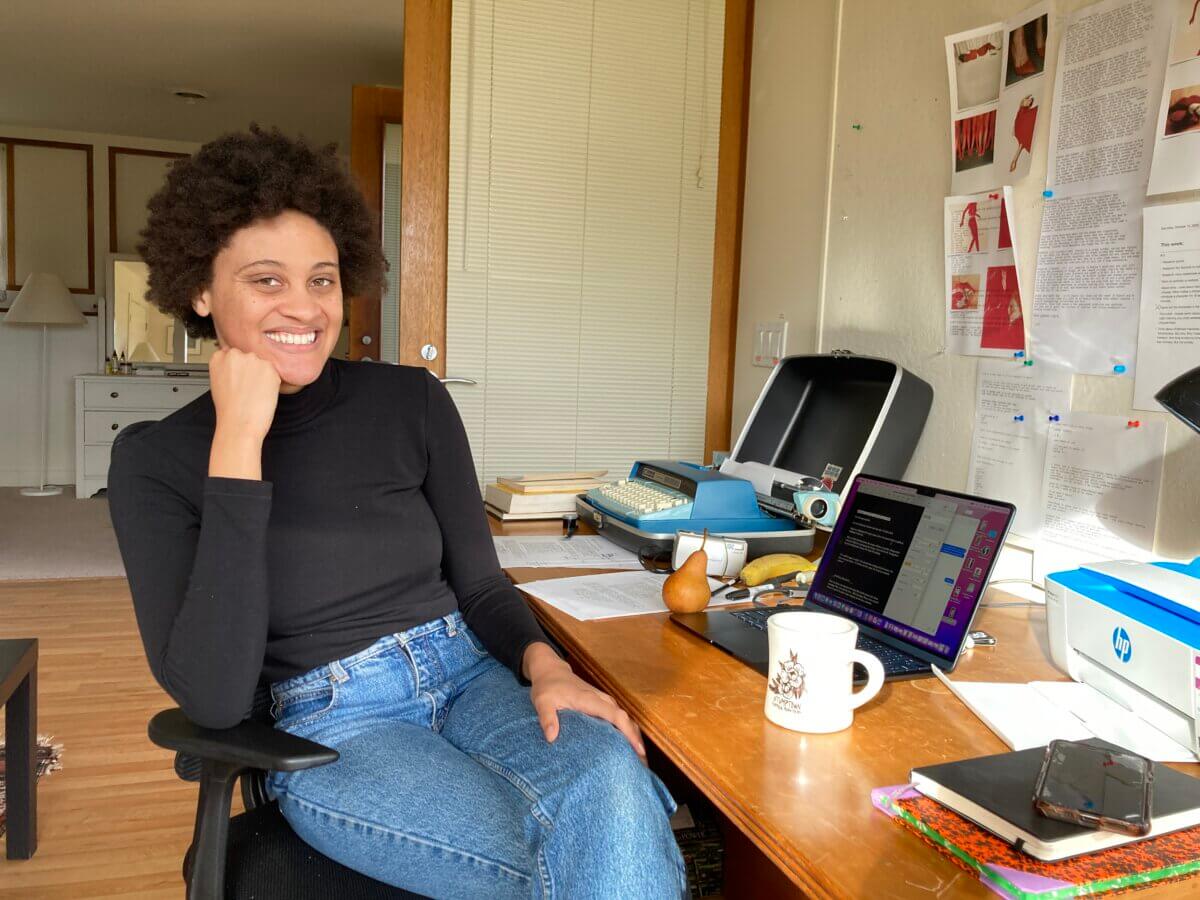 filmmaker Suliya Gisele sits at her Saltonstall desk smiling with her chin on her hand