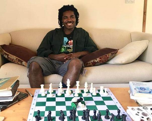 Grace Kim, smiling, sitting at a desk filled with colored pencils and a large work-in-progress